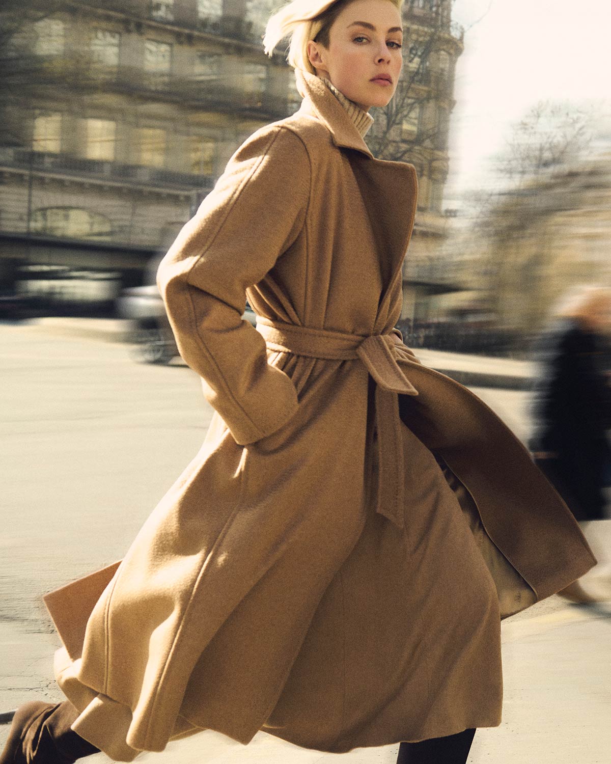 Model in Max Mara Manuela icon coat in camel colour, tied at the waist in an elegant and dynamic city style.